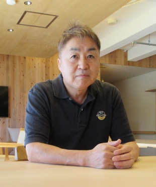 椅子に座りこちらを向く青山